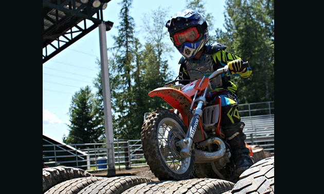 Six-year-old Kale Cuthbertson just started competing in 2012; he is currently in the peewee advanced class. <br /><strong>- Charla Cuthbertson photo</strong> A little kid riding a red dirt bike over a log.