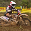 A woman dirt biker riding through mud