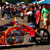 A shiny orange chopper style motorcycle at a festival. 