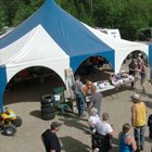 Photo of a blue and white tent and lots of people milling around it. 