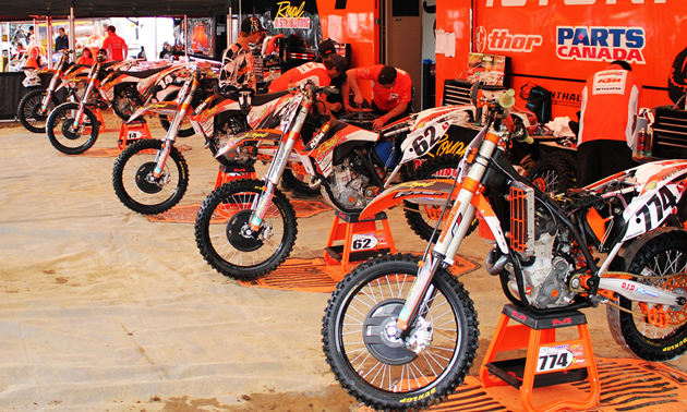There's nothing cooler than a row of factory race bikes under the big tent at the nationals. Half a dozen orange dirt bikes parked in a line beside a trailer under an orange tent.