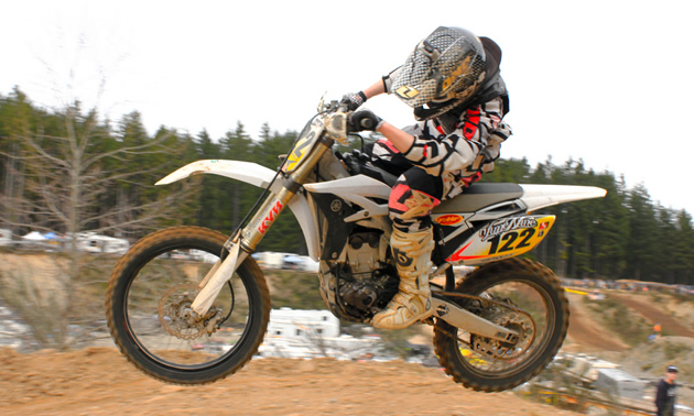 Photo of a guy in the air riding a white dirt bike.