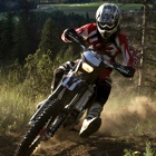 A dirt bike rider on a trail with a scenic valley and lake behind