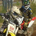 Photo of two young kids on dirt bikes coming around a corner.