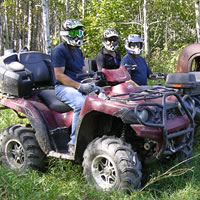 Several people pose on their muddy ATV's for a picture.