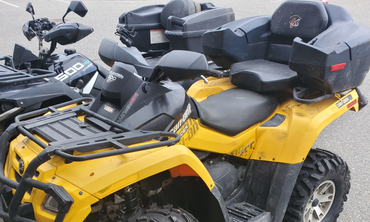 A yellow ATV with a seat attachment on the back. 
