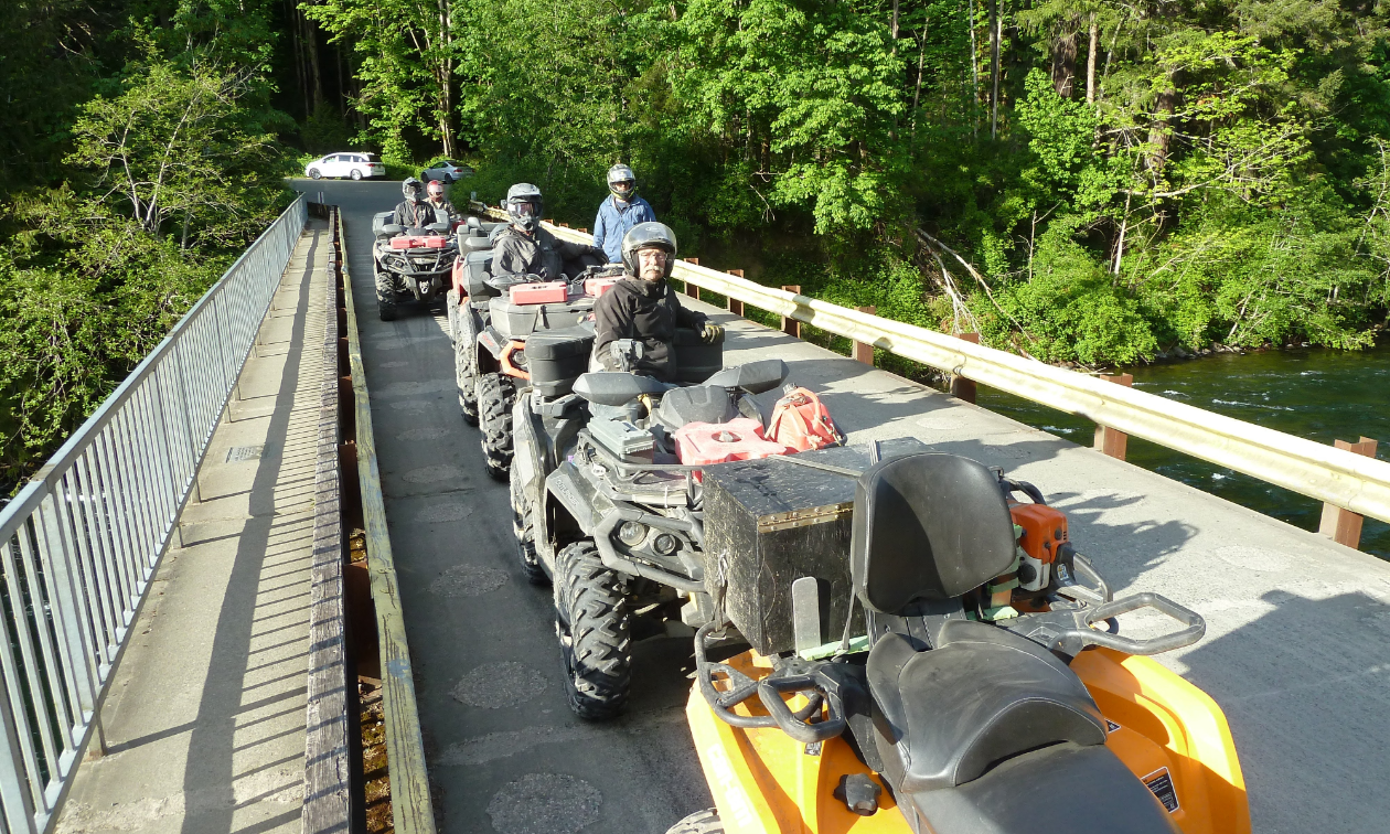 A bridge filled with ATVs in the woods. 