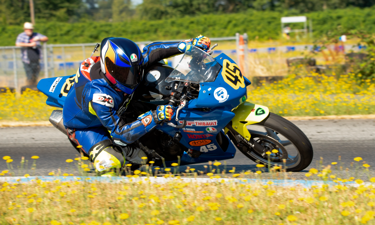 Andrew Van Winkle leans into a tight turn on his blue Honda CBR250R motorcycle on a race track. 