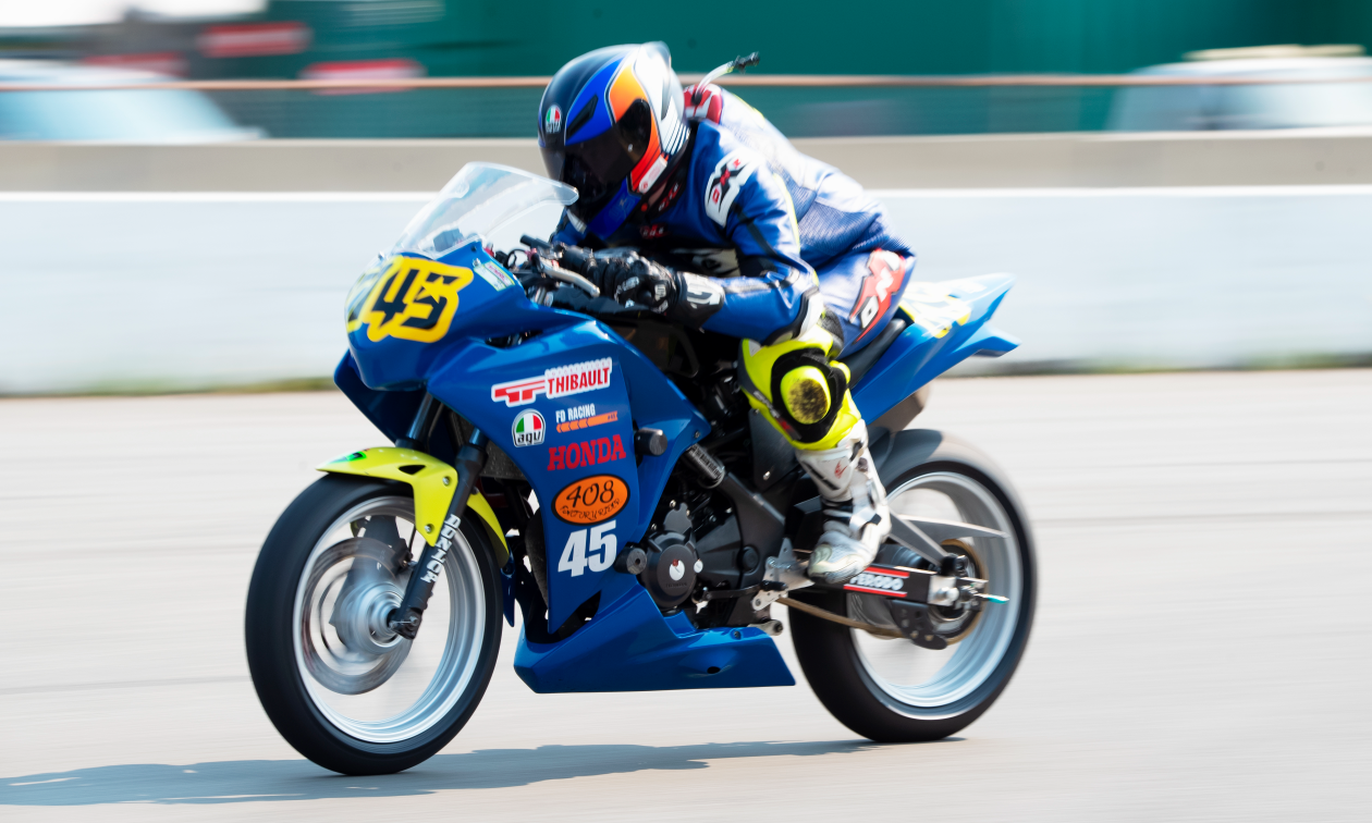 Andrew Van Winkle rides a blue Honda CBR250R motorcycle at high speeds on a race track. 