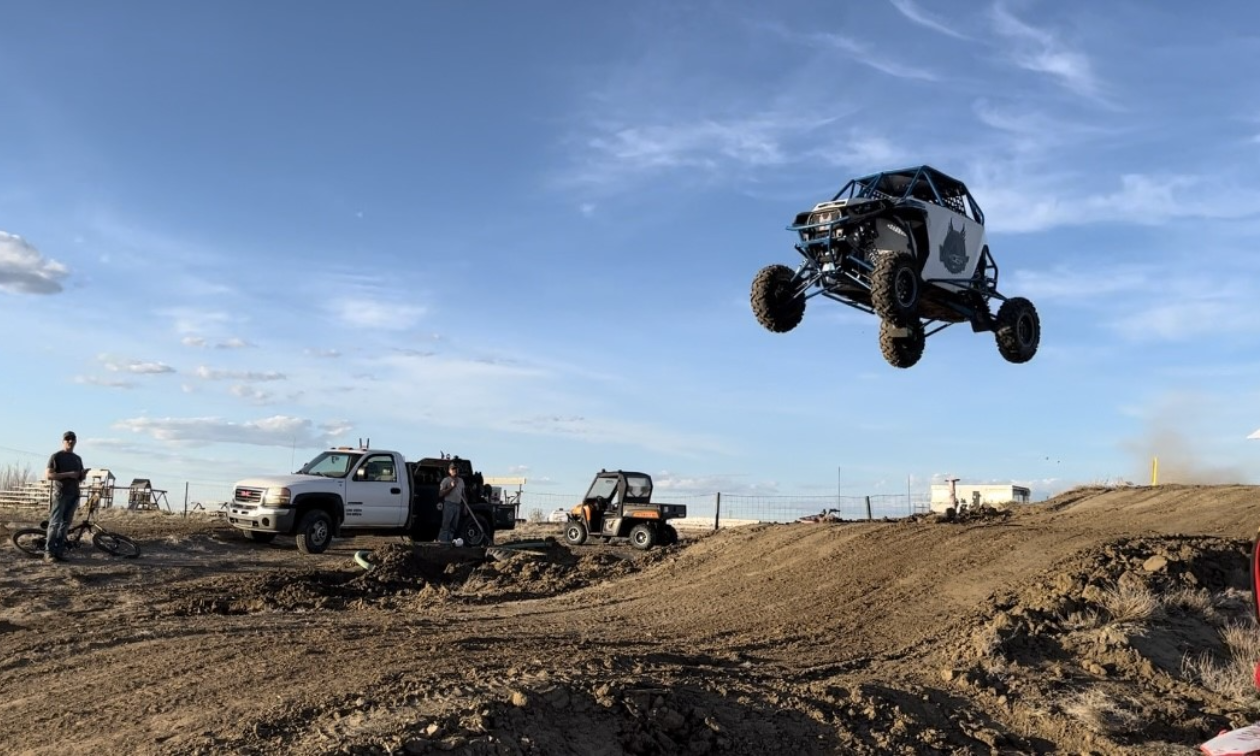 A Polaris RZR gets several metres of air off a big jump on a dirt race track. 