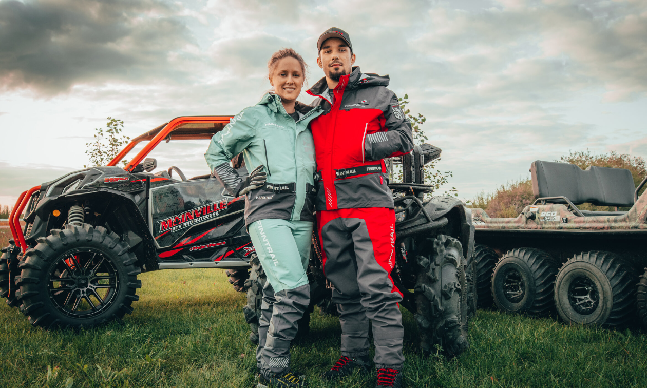 Cassandra and Kyle Mainville stand next to each other in front of a red and black ATV and trailer. 