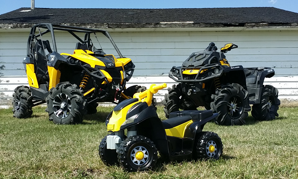 ATVs Maverick and 650 XMR behind a small battery-powered quad with a custom paint job to match the Can-Am black and yellow.