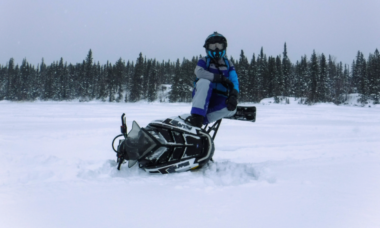 A woman sits on the side of her Polaris 600 RMK snowmobile. 