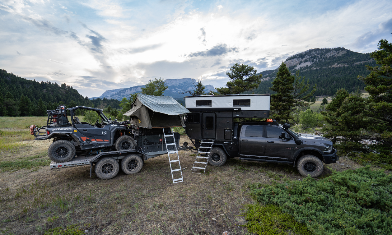 In a glade in Montana, a Dodge Ram 3500, carrying a Patriot Camper TH610 trailer with a Polaris General 1000.