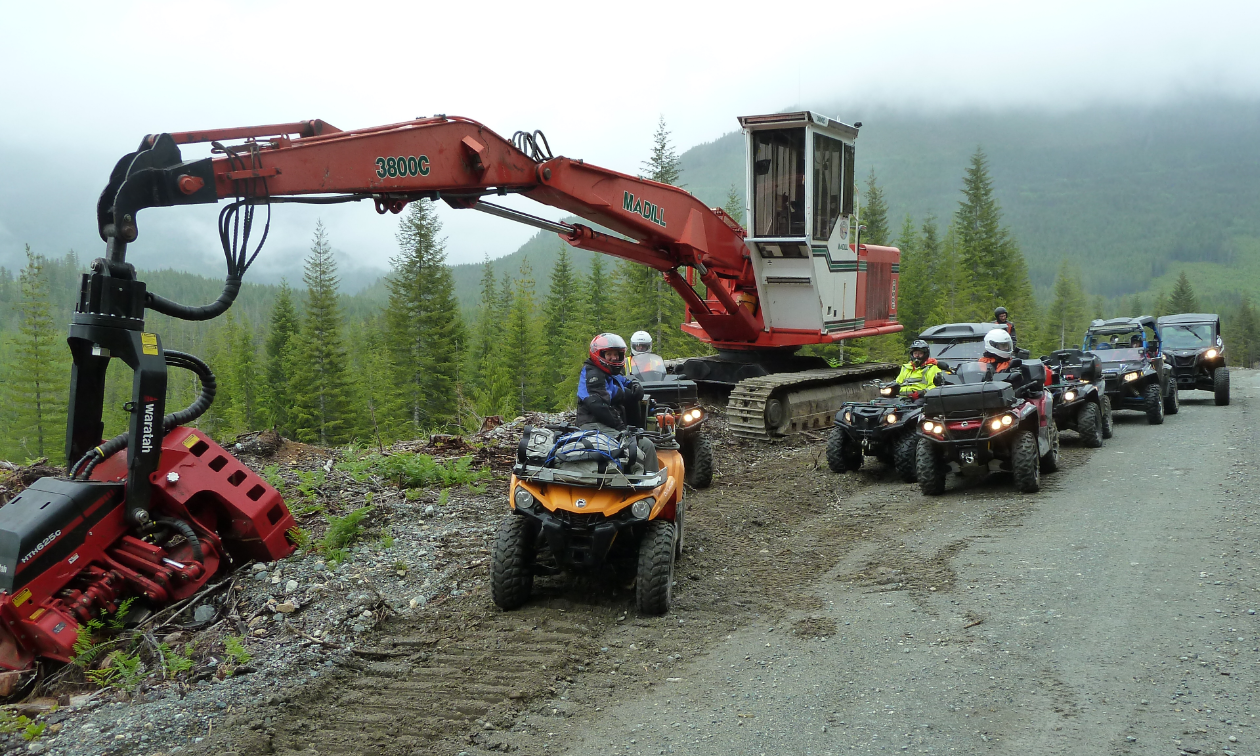 Quadders take a break to check out the Madill 3800 log harvester on the side of the road.