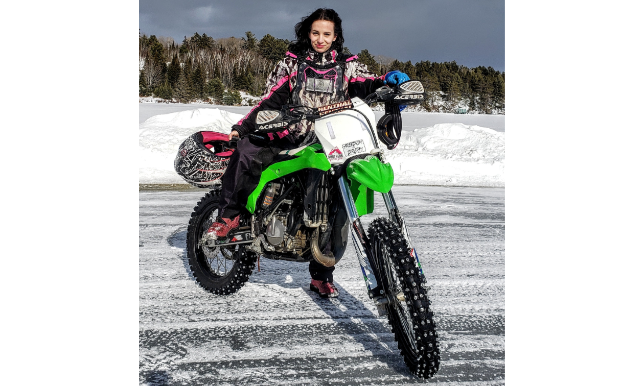 Jessica Rainville poses on a green dirt bike on ice.
