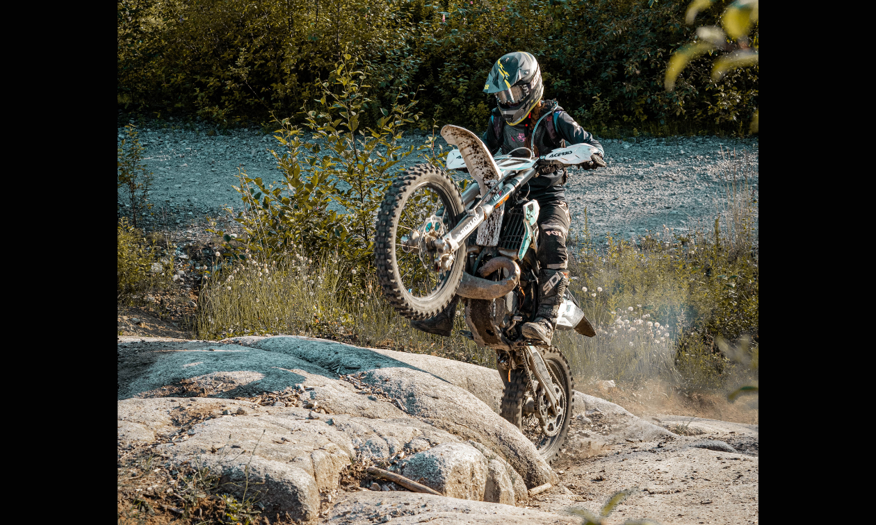 Kela Louise takes her dirt bike for a wheelie up onto a rock on the McNutt enduro trails.