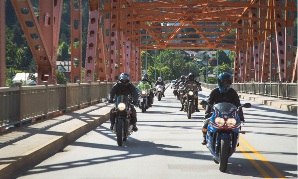 Motorcyclists drive over a big bridge with orange beams in Nelson, B.C.