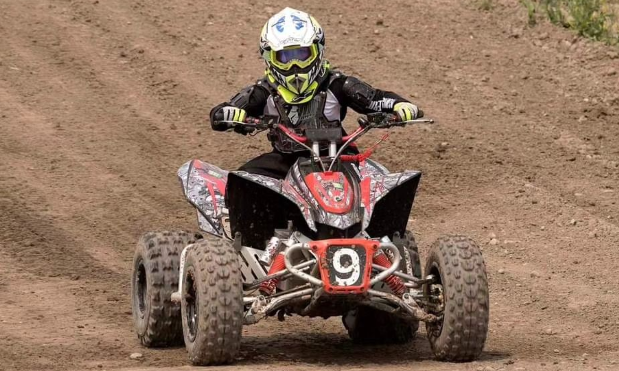 Theo Kumson races his red and black electric ATV down a track.
