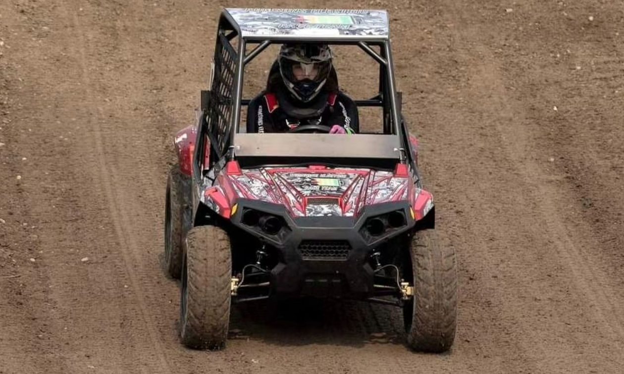 Savannah Kumson rides her red and black ATV towards the camera on a race track. 
