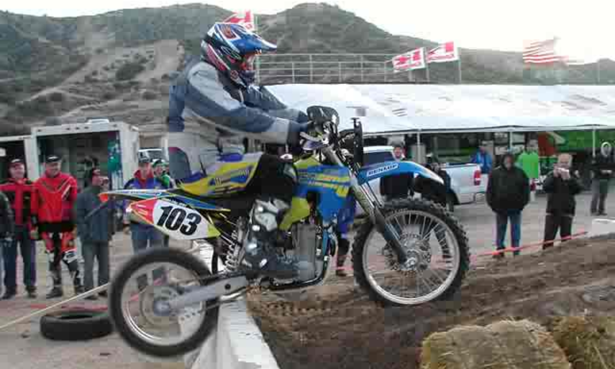Lee Fryberger rides a motorcycle over a barricade during a competition.