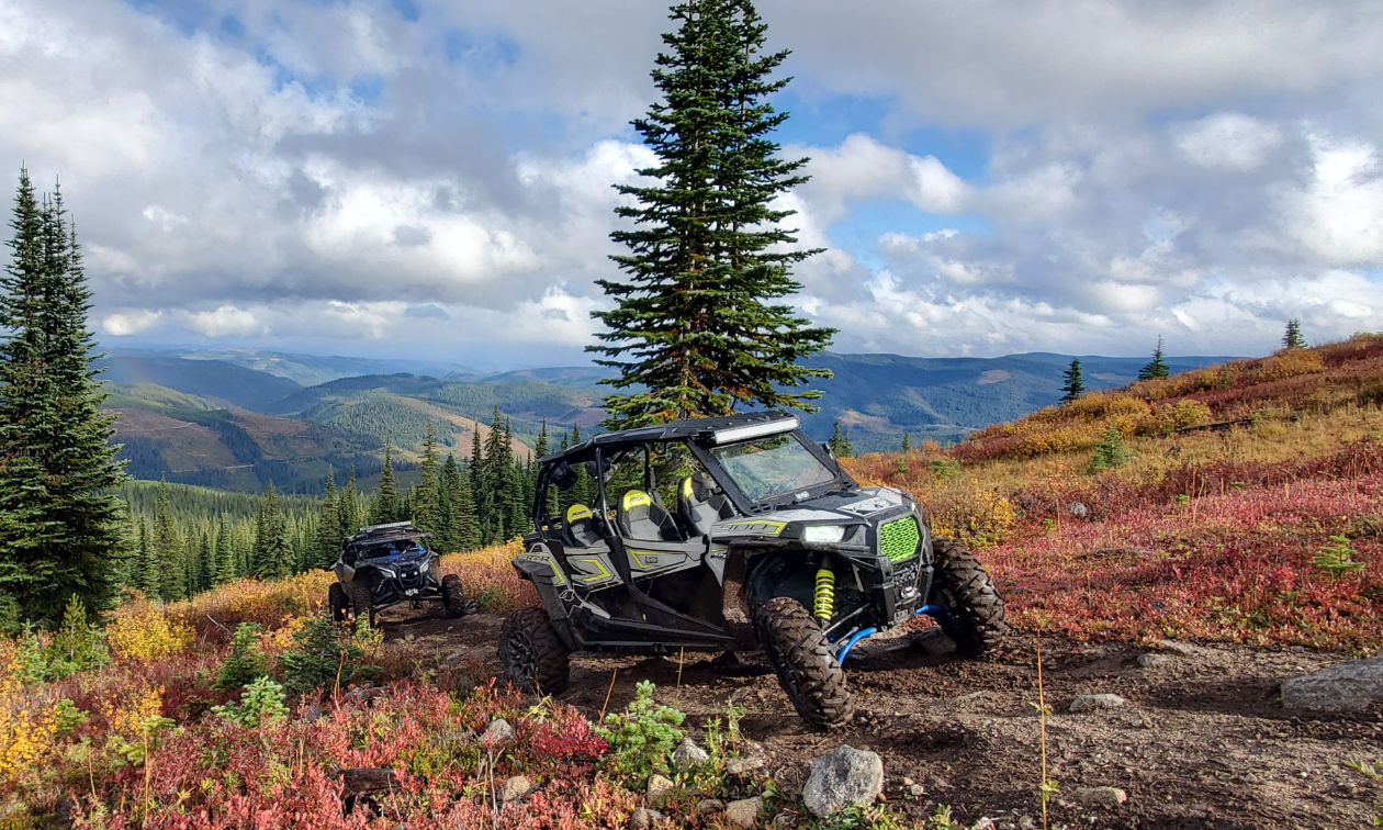 A 2018 Polaris RZR S4 900 is parked on a trail high in the mountains on a cloudy day.