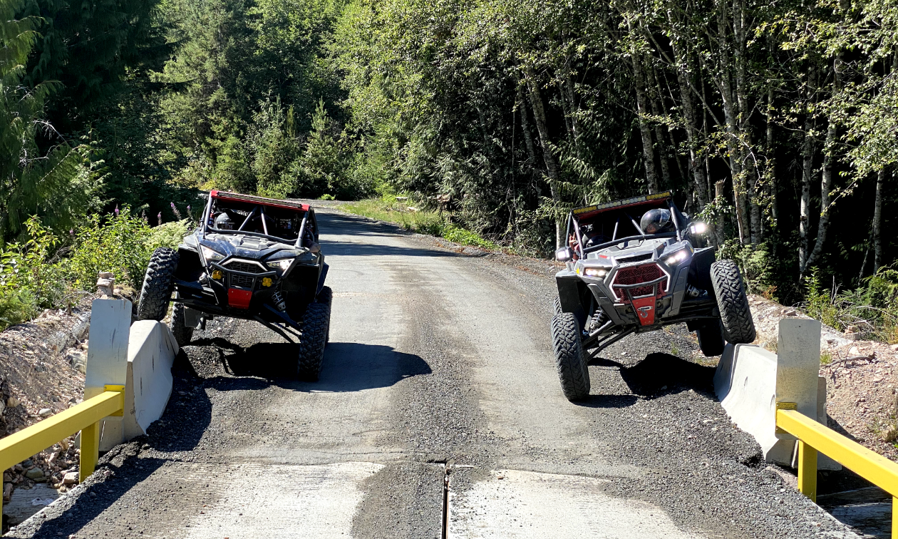 Two ATVs park at the end of a bridge on the North Island 1000.