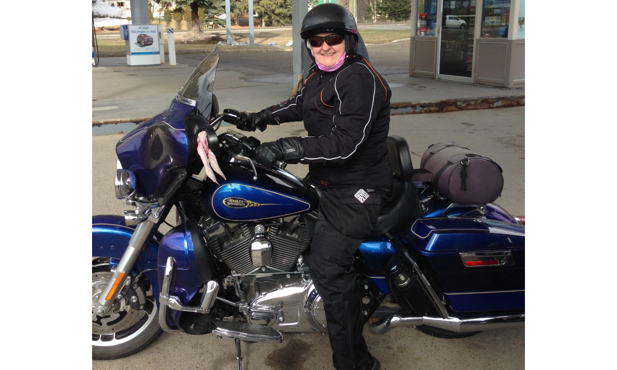 Nycole Ross rides a blue motorbike at a gas station.
