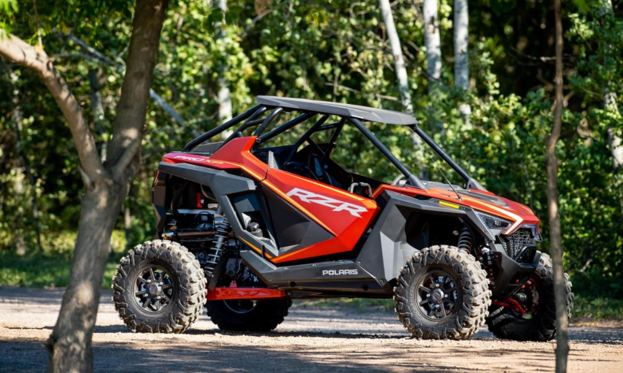 A red Polaris RZR on a trail in the woods.