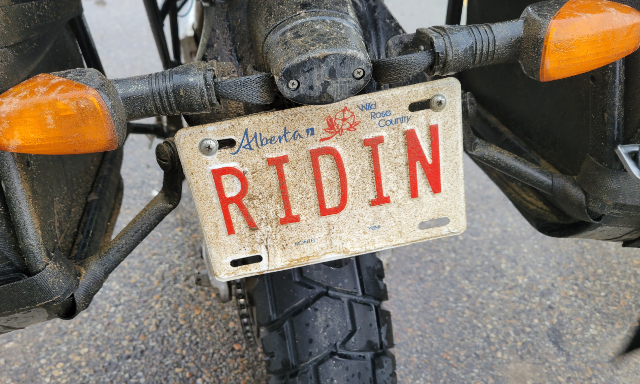 A motorcycle has an Alberta license plate that says Ridin. 