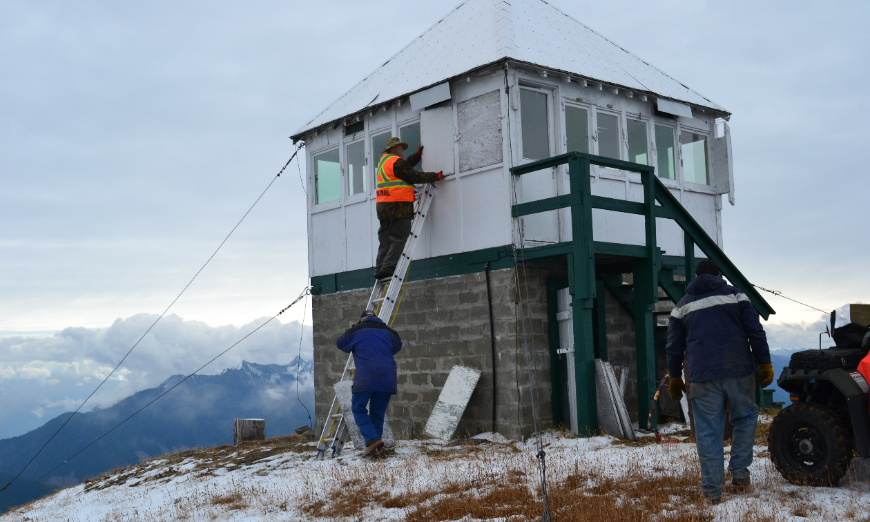 A group of people make repairs on the Sproat Mountain Fire Tower. 
