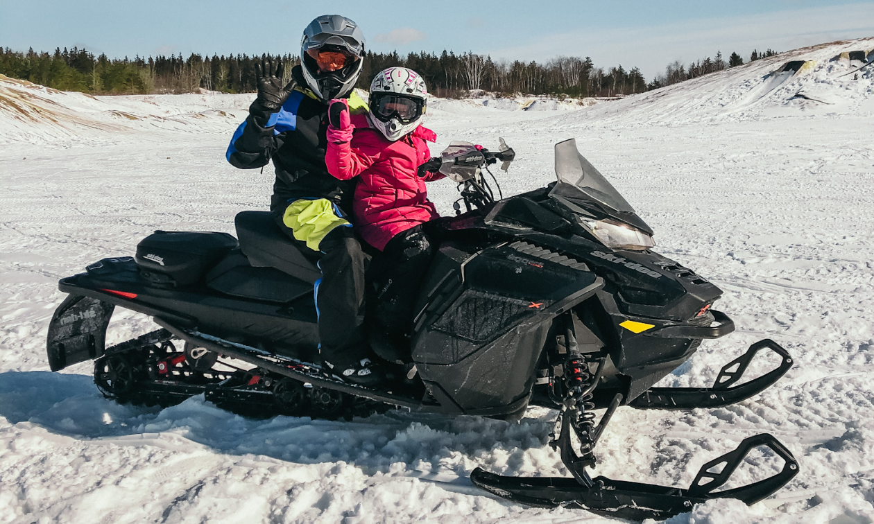 A man and little girl ride a black snowmobile on the plains in Manitoba. 