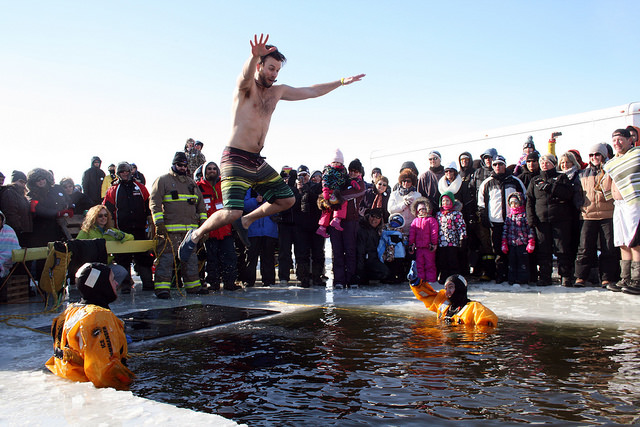 The first Polar Bear Swim at the Fort Winter Festival. Scott Fulton jumping ina small 12x12 square that had been cut in the ice for the Polar Bear Swim by volunteers.