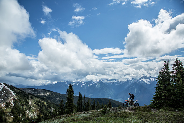 Steve Shannon riding on the mountain with a blue sky dotted with fluffy white clouds in the background.