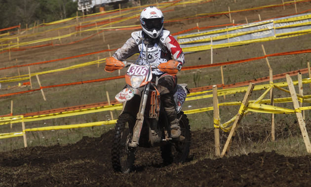 Photo of a girl riding around a dirt track on a bike. 