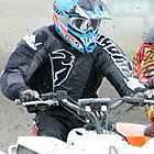 Photo of a guy in a black shirt and blue helmet racing an ATV. 