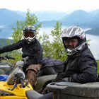 Two guys sitting on ATVs by a lake