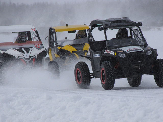 Three side-by-sides ice racing on a cloudy winter day. 