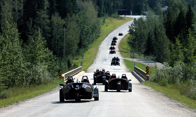 A group of Slingshot riders are cruising down a side road single-file.