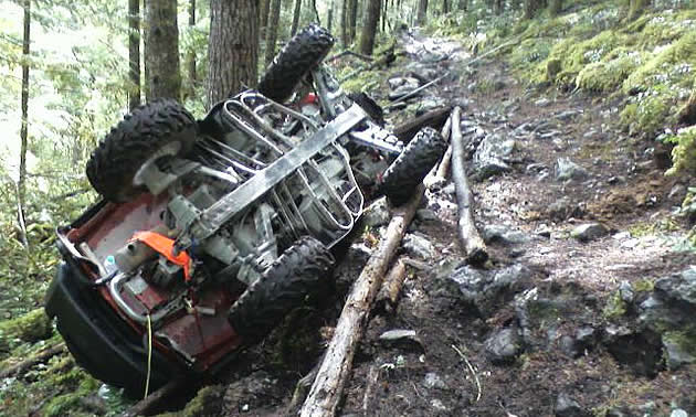 An ATV that's flipped over and hung up on a tree. 