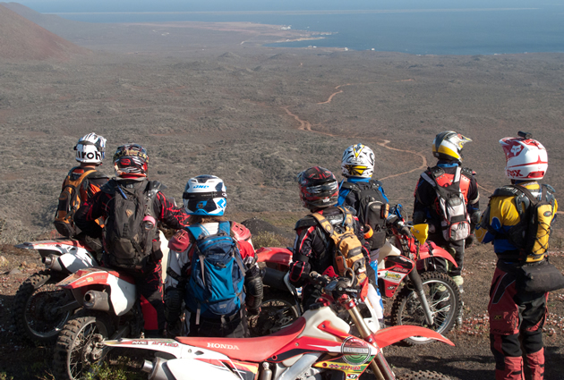 A group of motorcycle riders looking down at the Baja landscape. 