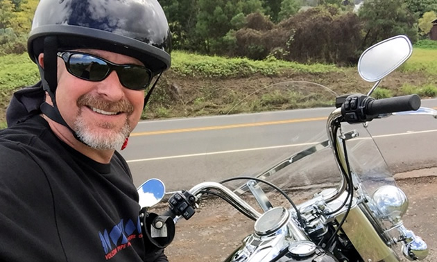 Roger Rhodes taking a selfie on a Harley-Davidson motorcycle. 
