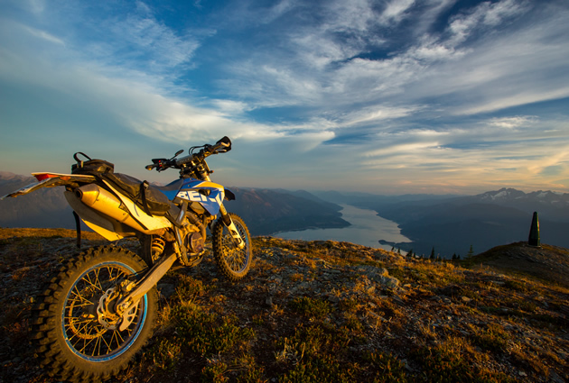 A dirt bike parked on the top of a mountain overlooking a large river. 