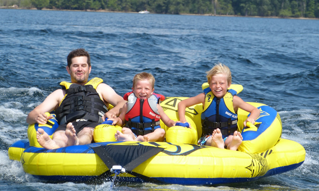 A man with two kids on a three-person inner tube. 