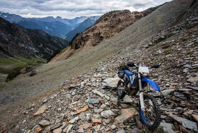 A dirt bike parked on the side of a rocky mountain. 