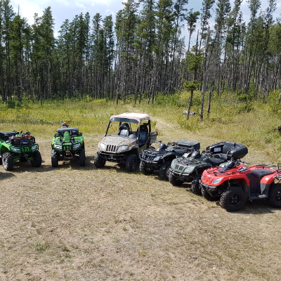 Gary Hora’s family owns a collection of quads, which are lined up in front of a forest.