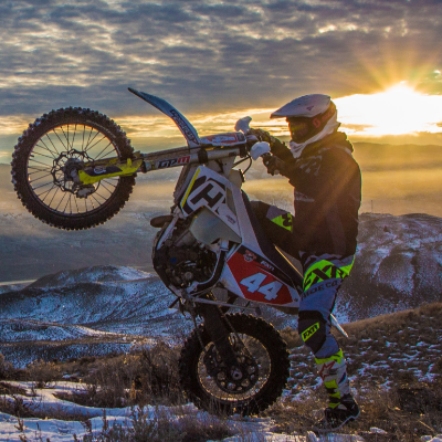 Dustin Labby does a wheelie while the sun breaks through the clouds behind him.