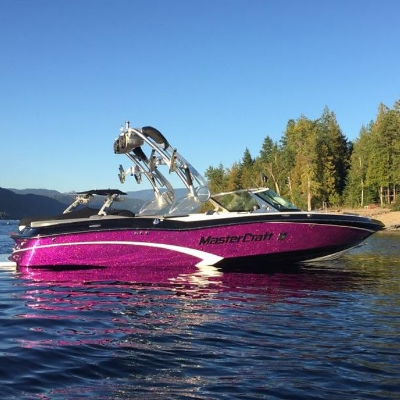A purple wakeboarding boat idles on a lake.