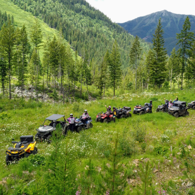 ATVs ride in a row in the foothills of nearby mountains.