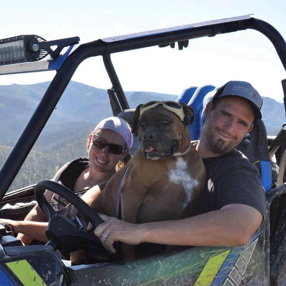 Lisa and Nathan Block smile from within their 2015 Polaris 900 RZR while their boxer Brooklyn sits on Nathan’s lap.